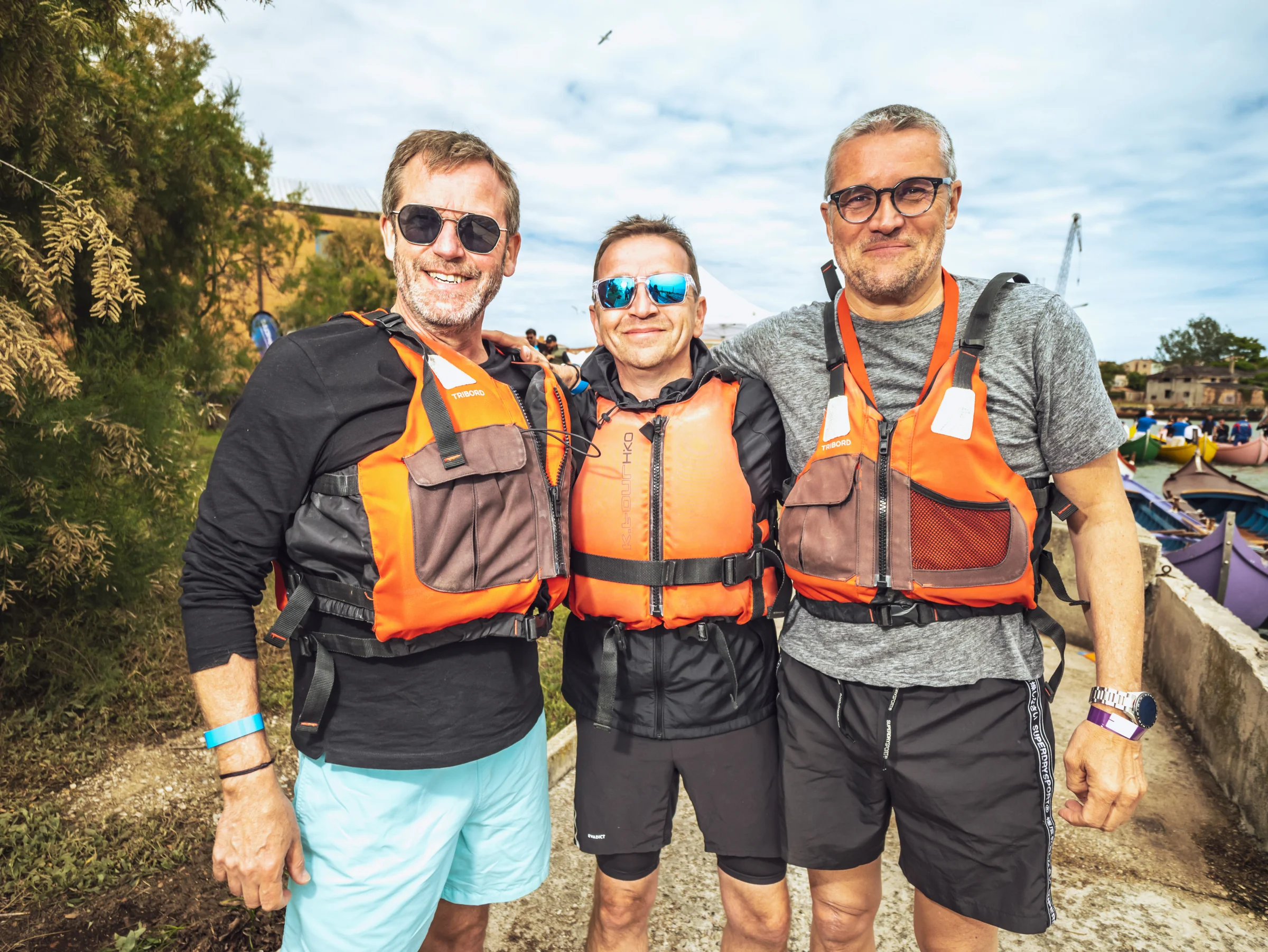 Trois participants équipés de gilets posent avant une activité nautique.
