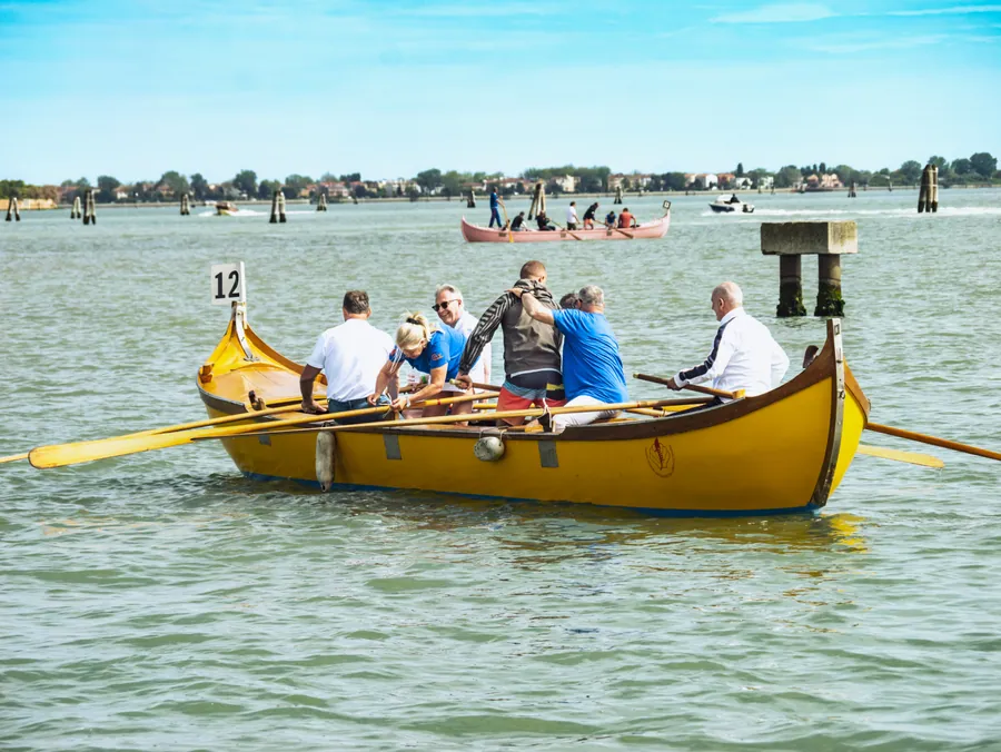 Une embarcation jaune et son équipe sur la lagune de Venise