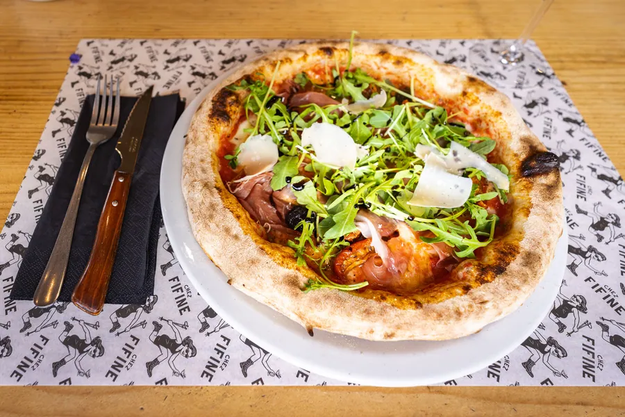 Pizza garnie de roquette et de copeaux de fromage chez Fifine