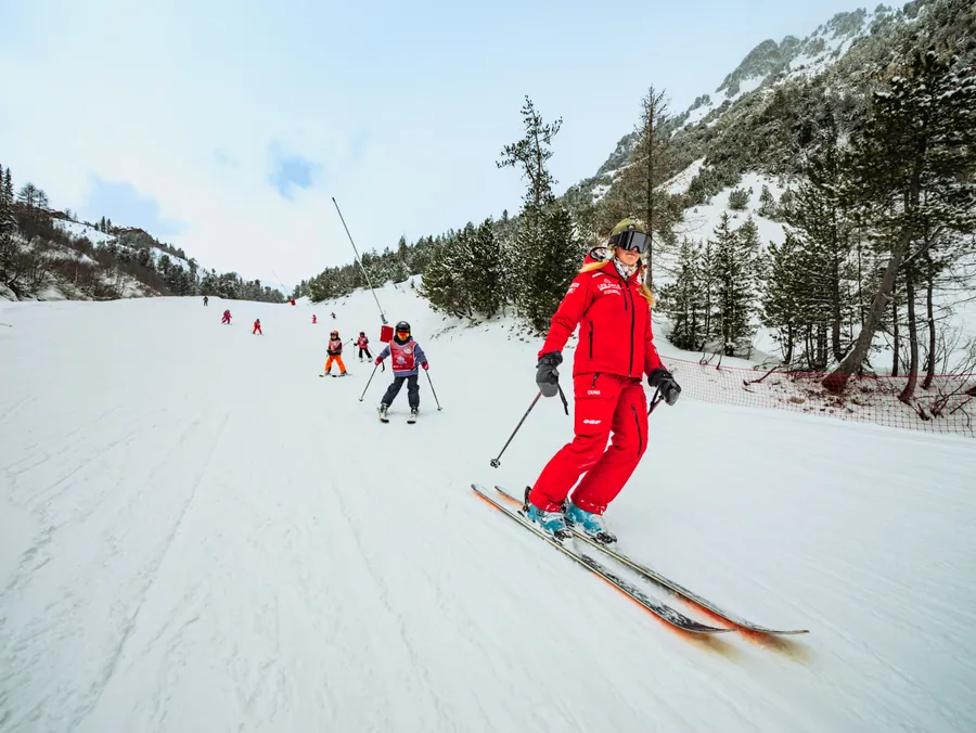 Une jeune skieuse sur la piste bordée de sapins