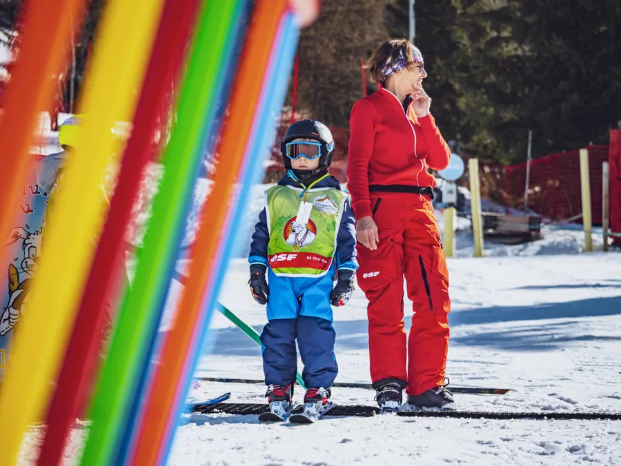 Le moniteur accompagne un enfant entre les piquets