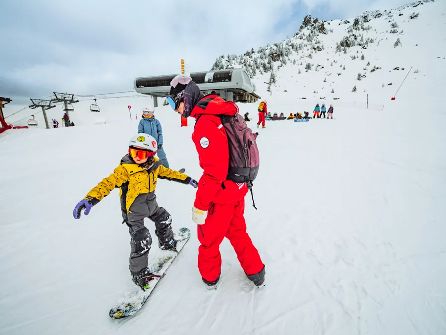 Le moniteur accompagne les enfants en snowboard