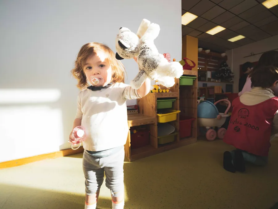 Une peluche dans les bras, dans la lumière de la fenêtre