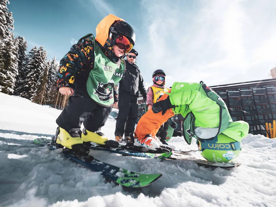 Le moniteur aide les enfants à préparer leurs skis