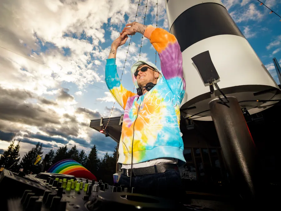 Un DJ lève le bras au-dessus de ses platines sur la terrasse des Arcs