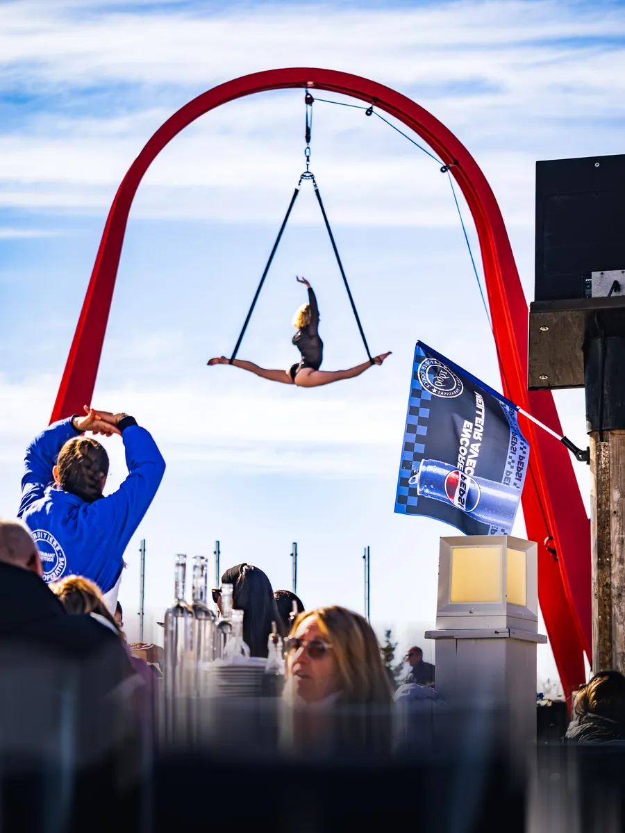 Une artiste aérienne suspendue sous l’arche rouge de La Folie Douce