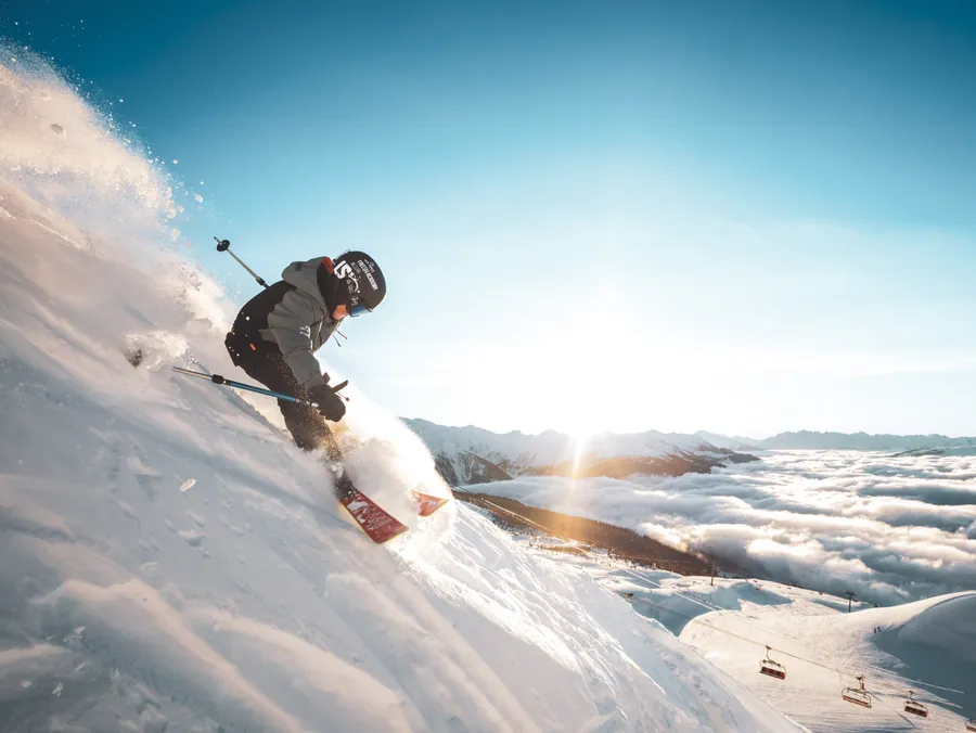 Un skieur dans la lumière au-dessus d’une mer de nuages