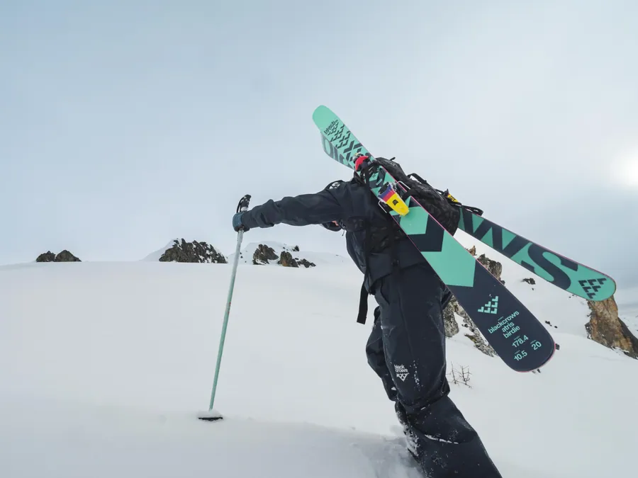 Un rider porte ses skis entre deux descentes