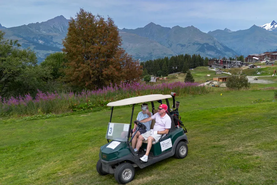 Des participants dans une voiturette de golf pendant la compétition L’Entrepotes au Golf des Arcs