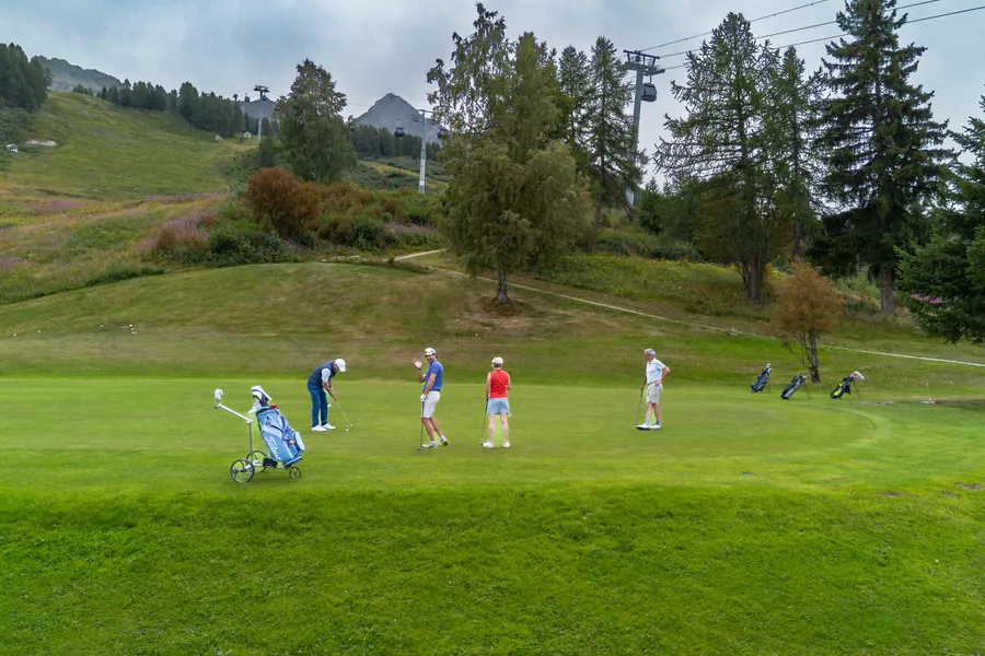 Des joueurs sur le green au milieu des arbres pendant la compétition L’Entrepotes au Golf des Arcs