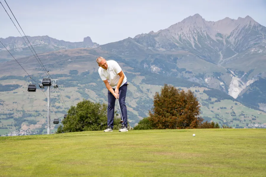 Un joueur sur le green face aux montagnes pendant la compétition L’Entrepotes au Golf des Arcs