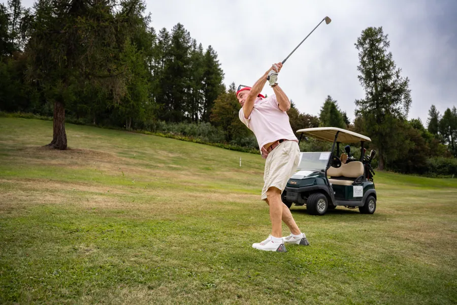 Un joueur frappe sa balle près d’une voiturette pendant la compétition L’Entrepotes au Golf des Arcs