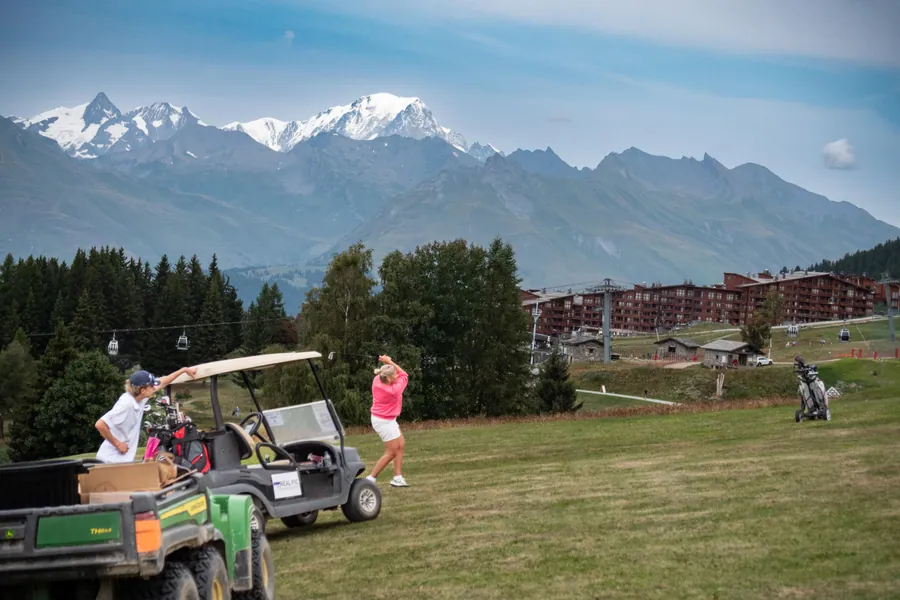 Une voiturette sur le parcours face aux sommets pendant la compétition L’Entrepotes au Golf des Arcs