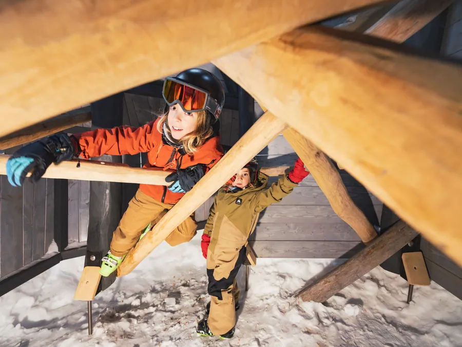 Un enfant explore l’intérieur d’une structure en bois aux Géants de Malgovert, Les Arcs