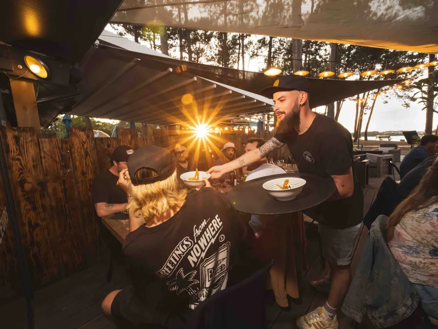 Un serveur apporte les assiettes en terrasse à Otra Cosa, Soustons plage