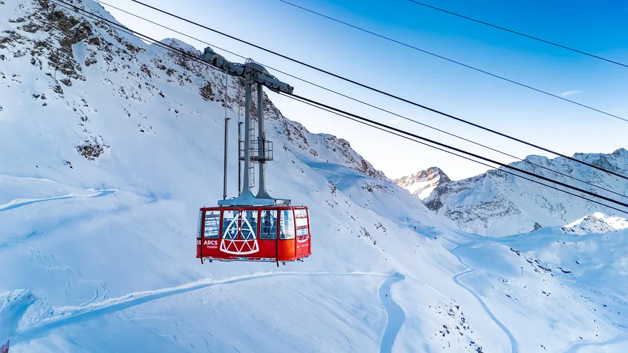 Le téléphérique traverse le paysage enneigé de l’Aiguille Rouge