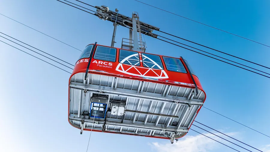 La cabine rouge suspendue sous les câbles dans le ciel bleu