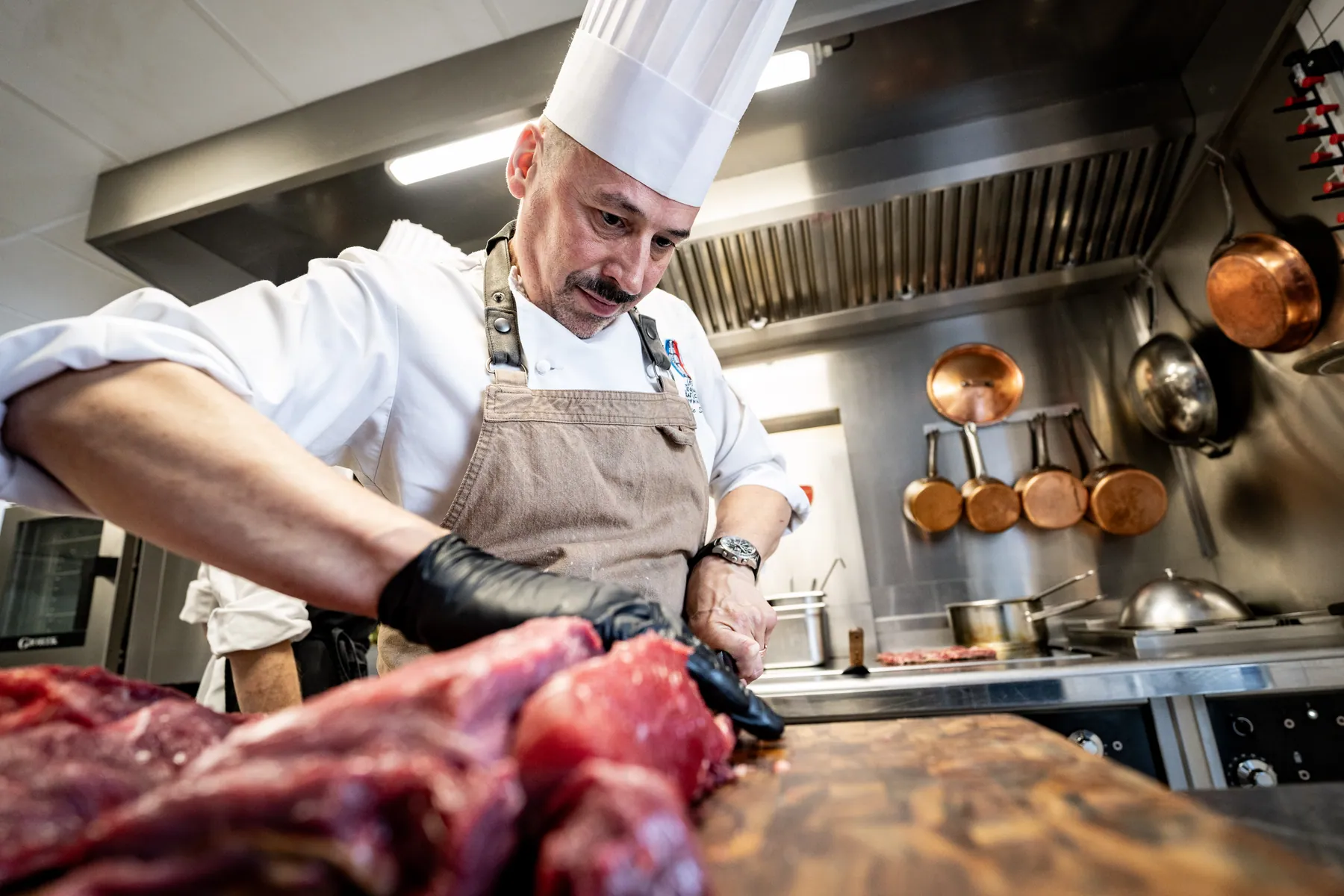 Le chef travaille la viande en cuisine à La Table de la Coop