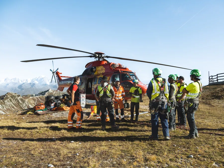 Briefing de l’équipe devant l’hélicoptère sur le chantier du Transarc